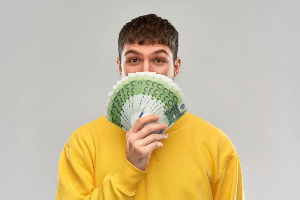 homme tenant une série de billets de 100 Euros dans les mains