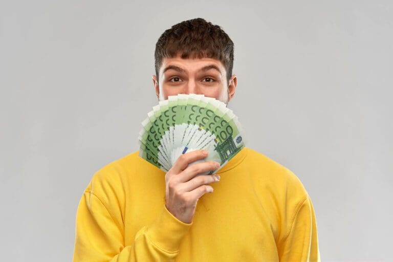 homme tenant une série de billets de 100 Euros dans les mains