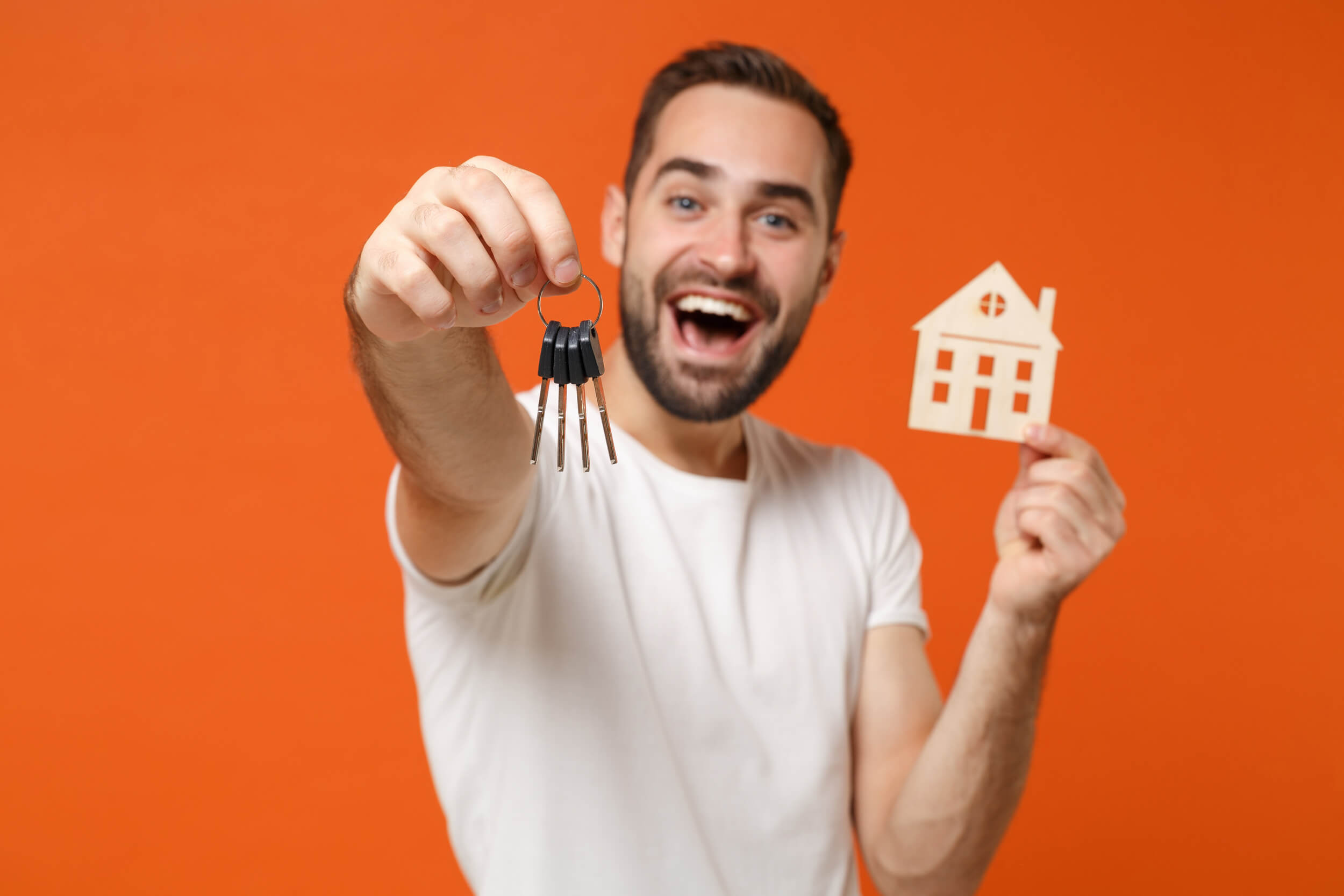 homme qui tient des clés et une petit maison dans ses mains