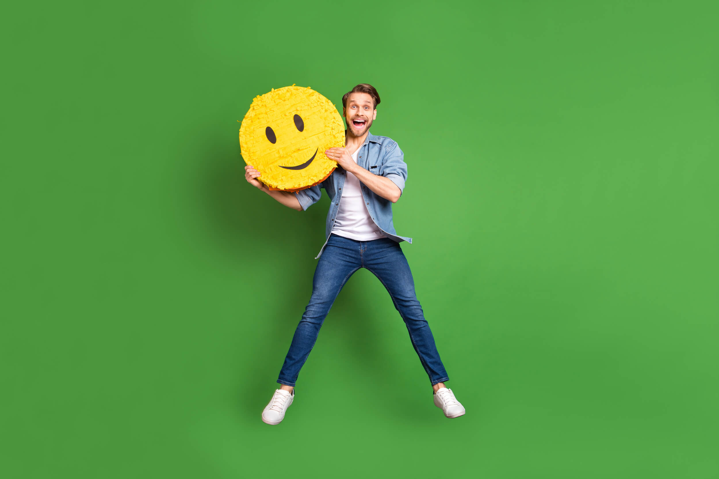 homme heureux saute avec un smiley géant entre les mains