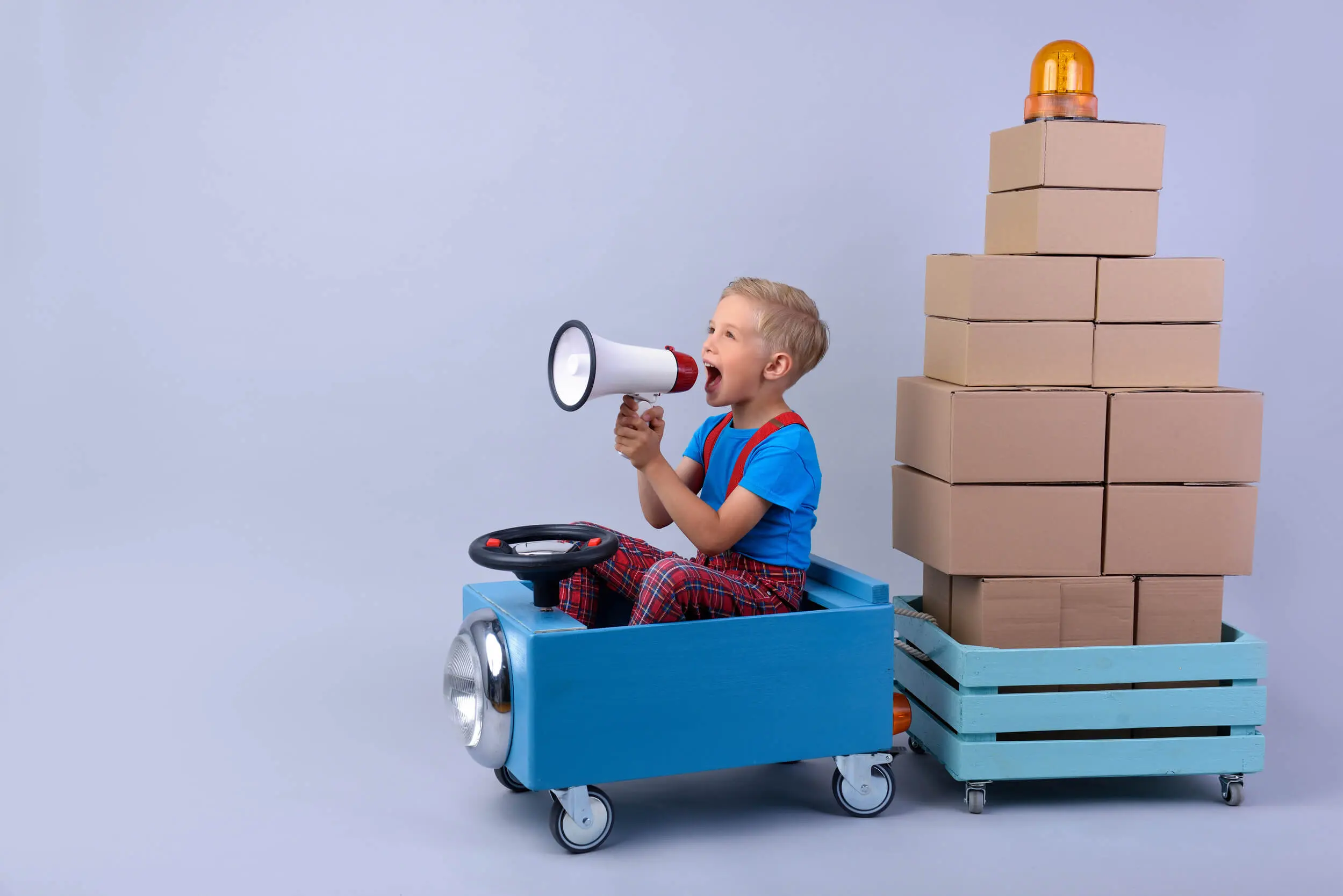 enfant dans un petite camion transportant des cartons dans une remorque